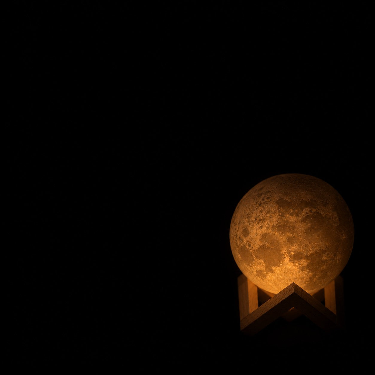 La Petite Lune presque éteinte dans le noir, sur son support en bois